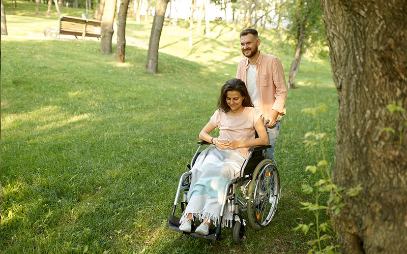 Man pushing woman in wheelchair