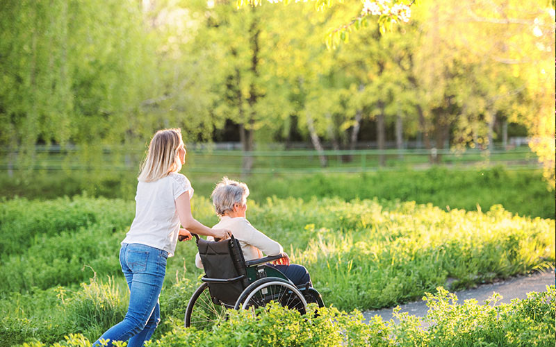 Lady in wheelchair being pushed through park