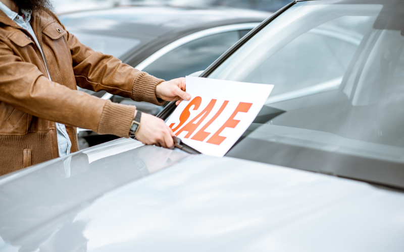 Person placing sale sign on a car