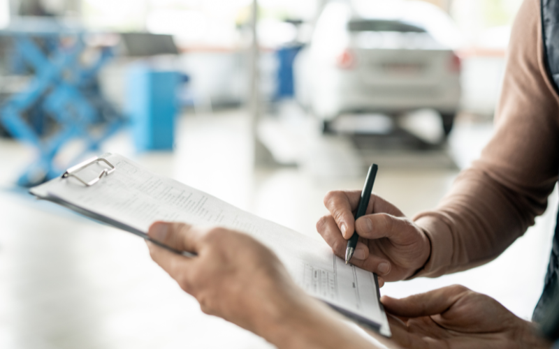 Technician handing over invoice for car service to a customer to sign
